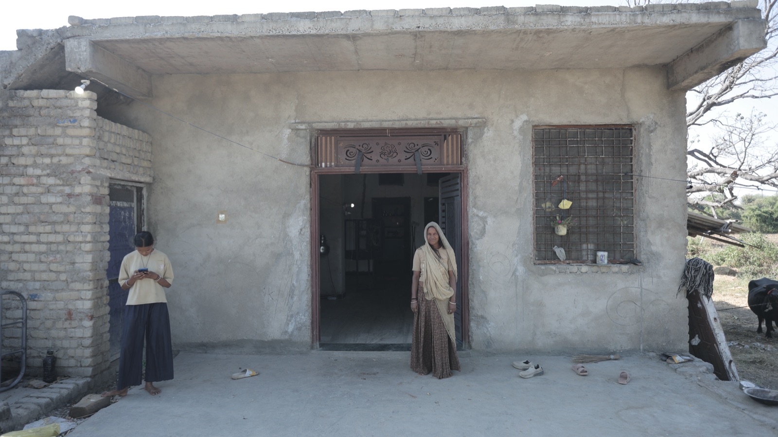 A woman standing in the doorway of a cement home
