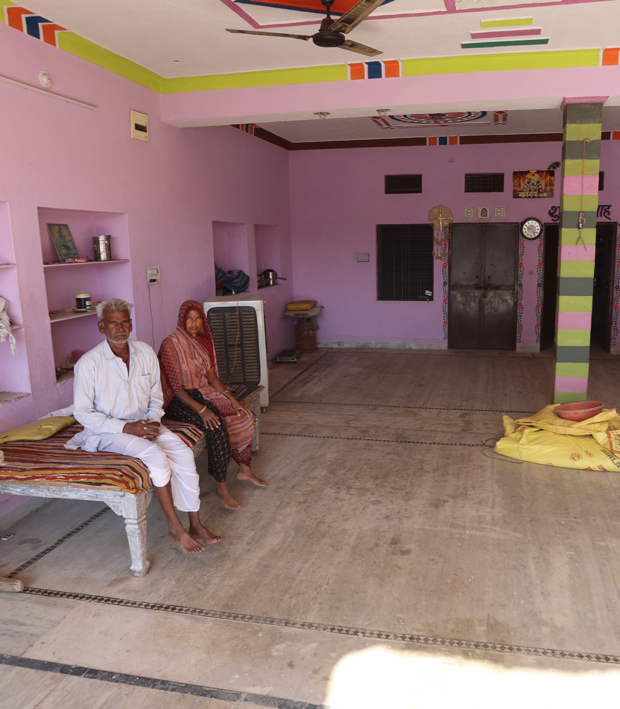 A couple seated inside their home in a rural community